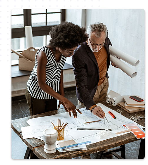 Un homme et une femme collaborent sur des plans d'architecture et de décoration d'intérieur, examinant les détails sur une table remplie de documents, d'outils de dessin, et de maquettes, dans un bureau lumineux.