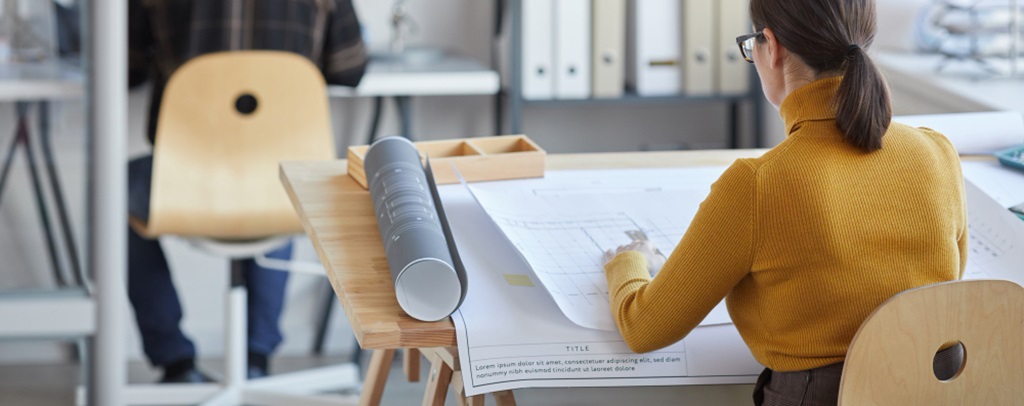 une femme de dos assise sur un bureau