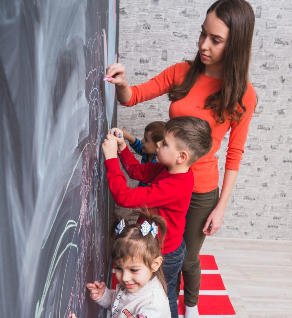 une jeune femme en stage petite enfance travaillant avec des enfants sur un tableau noir