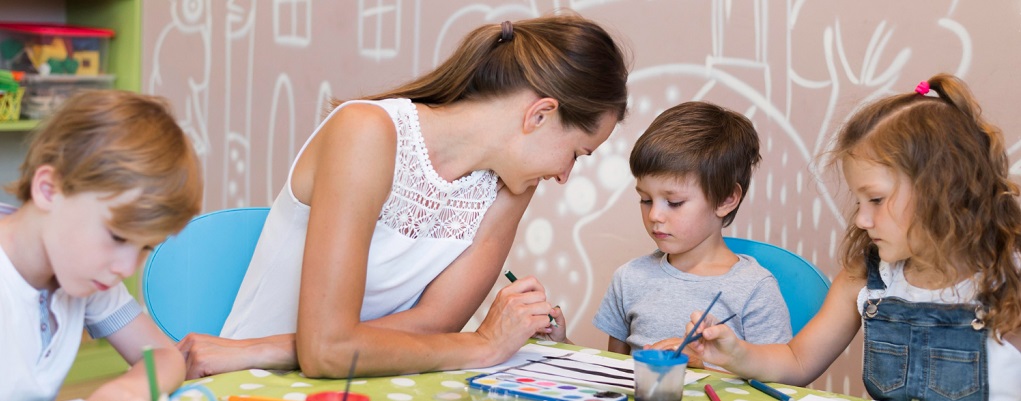 une atsem qui anime une activité avec 3 enfants