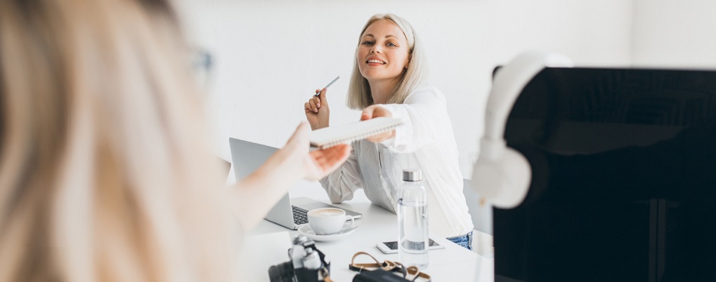 Une femme qui tend un carnet à une élève en formation